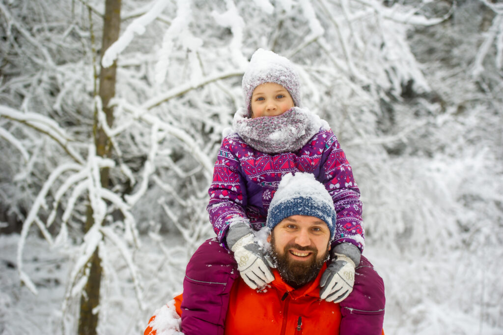 Family dad and daughter walk in the snow-covered forest in winter